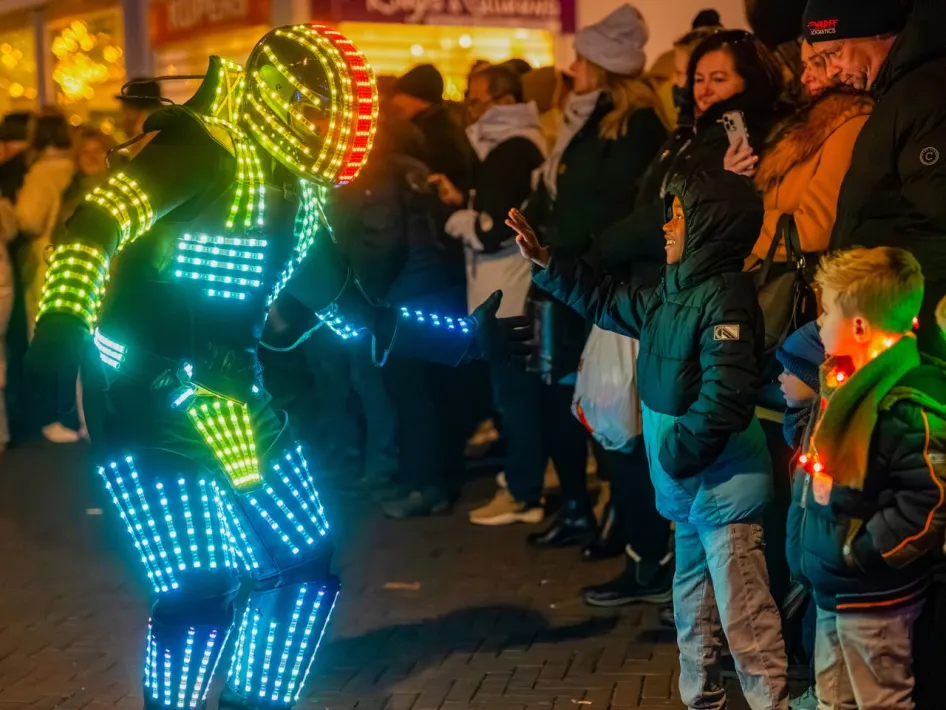 LED-artiest maakt contact met een kind tijdens een verlicht evenement.