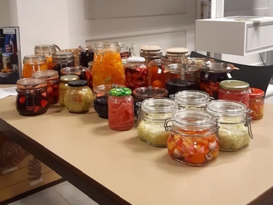 Glazen potten gevuld met verschillende soorten gefermenteerde groenten, waaronder wortelen, kool en andere kleurrijke seizoensgroenten.
