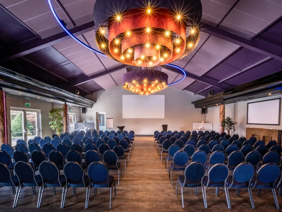 Zaal van Oolderhof in theateropstelling met schermen, geschikt voor congressen en zakelijke bijeenkomsten.