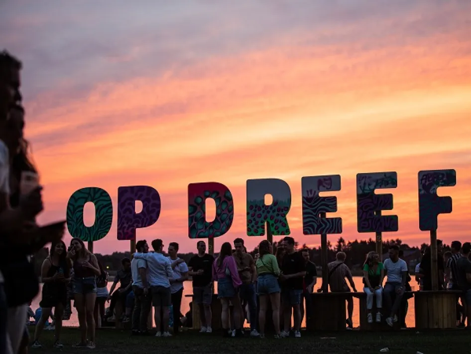 De letters die het woord Op Dreef vormen met mensen die erbij staan