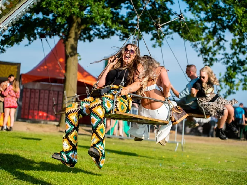 Vrouwen vermaken zich op de draaimolen van het Op Dreef Festival 2025