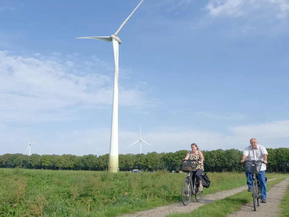 Open Energiedag bij windturbine De Coöperwiek, waar fietsers langs windmolens rijden door het landelijke landschap van Midden-Limburg.