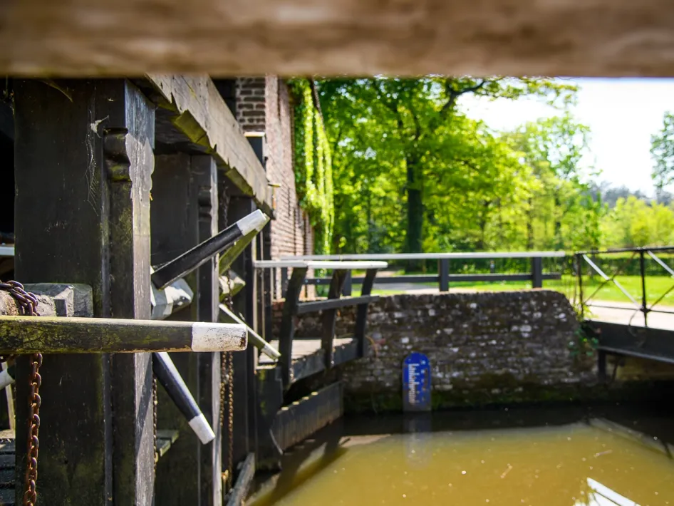 Houten onderdelen van de Leumolen in Leudal met water en groen op de achtergrond