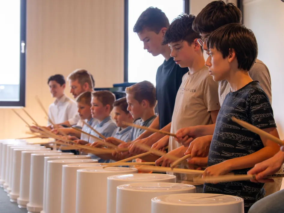 Jonge deelnemers spelen samen op trommels tijdens een workshop van het Percussion & Friends Festival.