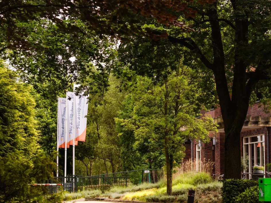 De vlaggen van Parc de Witte Vennen wapperen voor het receptiegebouw