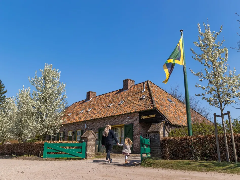 Peerkesbosch farmhouse in Nederweert with flowering trees and visitors at the entrance