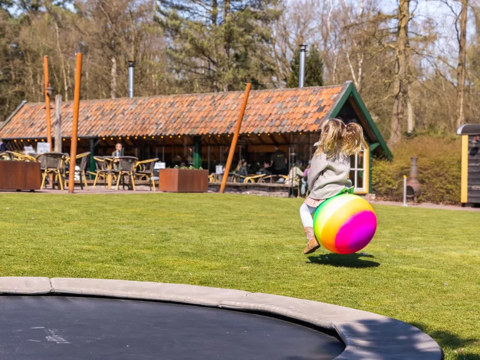 Kind speelt op een grote springbal op de speelweide van Peerkesbosch