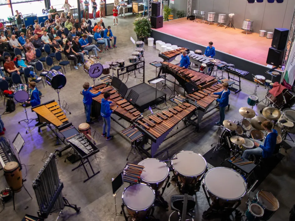 Overzicht van het Percussion & Friends Festival met slagwerkers tussen marimba’s, drums en ander slagwerk voor publiek.
