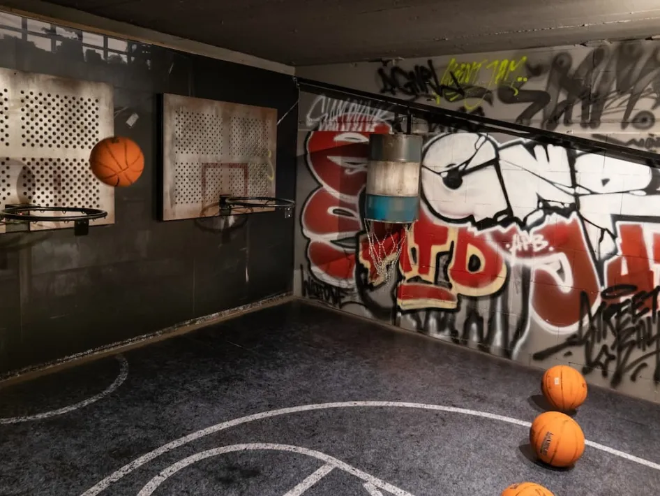 Bälle fliegen durch die Luft in einer coolen Indoorhalle mit Graffiti-Wänden und Metallkörben bei Poort51.