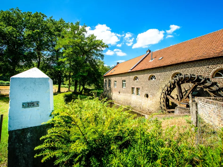 Die historische Gitstappermühle mit drehendem Wasserrad an einem sonnigen Tag.