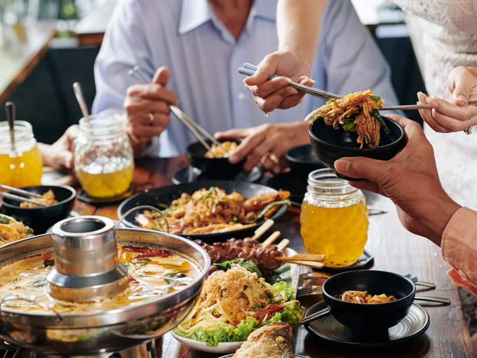 Gezellig dineren bij Burgers Enzo met een tafel vol Indonesische gerechten, waar gasten samen genieten van authentieke smaken.
