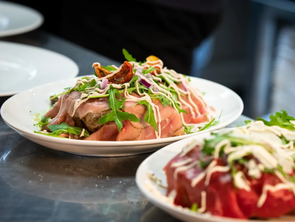 A plate with a Mediterranean dish of meat, rocket and sauce, freshly served from the kitchen.