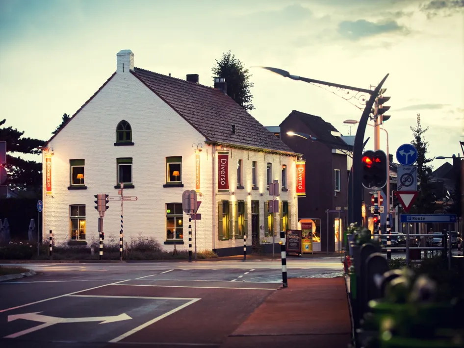 Restaurant Diverso in Nederweert, a white building on a street corner with lights and recognisable signage.