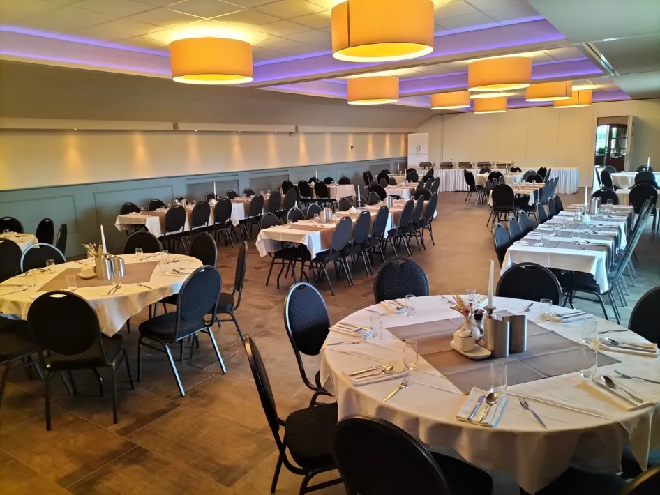 Spacious banquet hall with beautifully set tables and warm lighting.