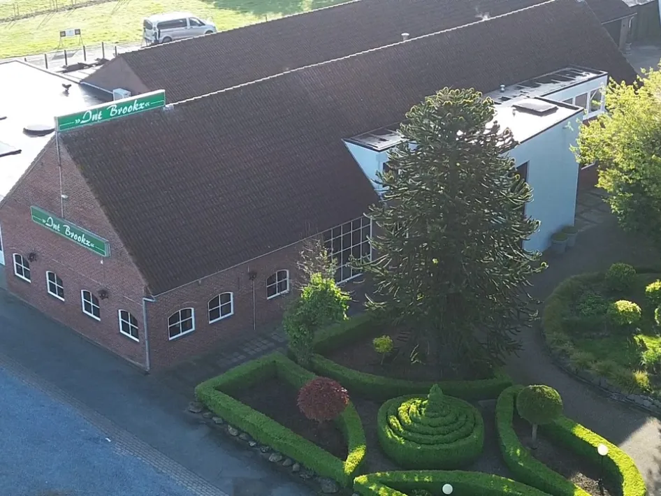 Luchtfoto van Restaurant Int Brookx, omringd door een verzorgde tuin.