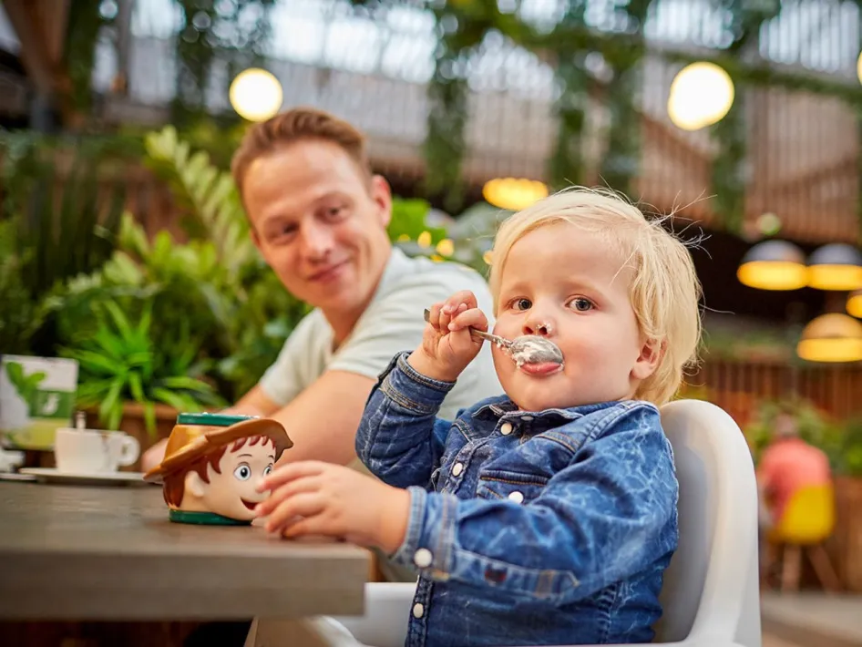 Klein kind eet ijs terwijl vader toekijkt in restaurant Via Verde bij De Leistert.
