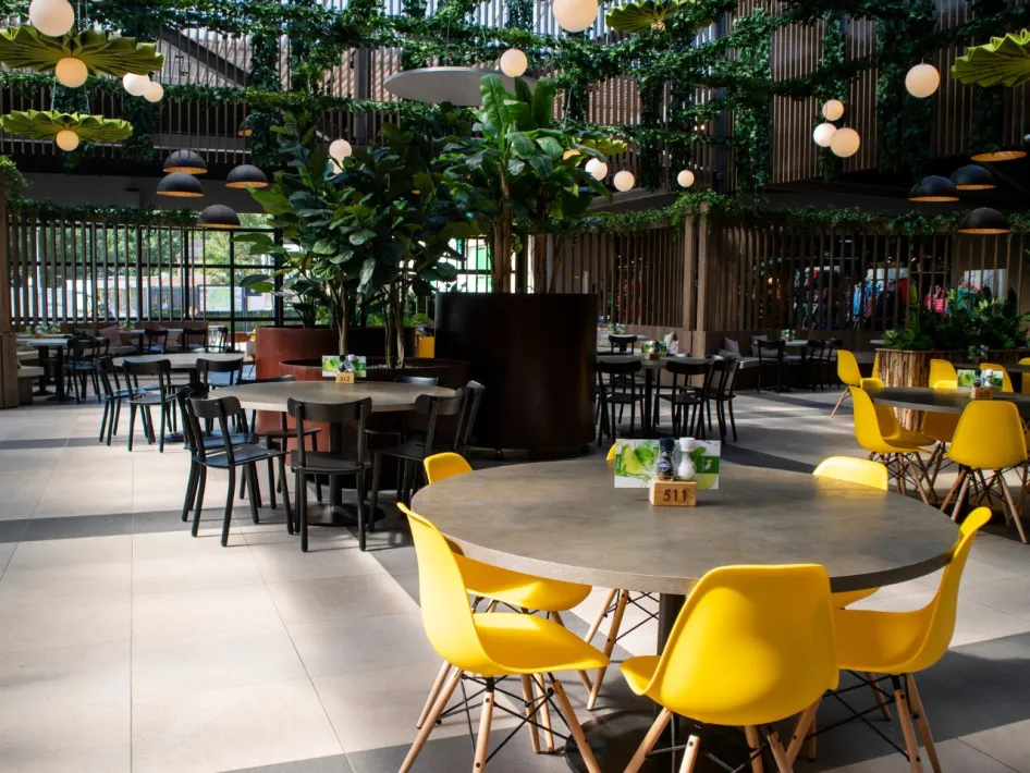 Interieur van restaurant Via Verde in De Leistert met gele stoelen en groene planten.
