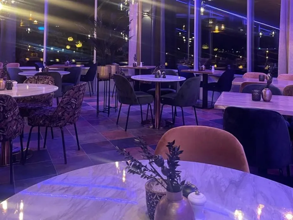 Dining room of Riverside Lounge with round tables and atmospheric evening lighting