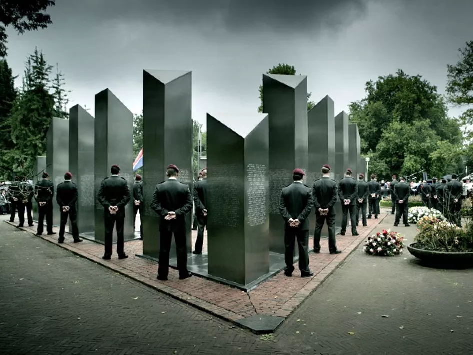Militairen staan in stilte opgesteld rond het Nationaal Indië-monument in Roermond tijdens de Nationale Indië Herdenking, met kransen en toeschouwers op de achtergrond.