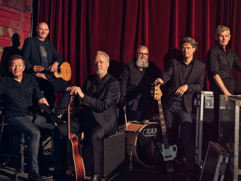 Rowwen Hèze met instrumenten voor een rood theaterdoek