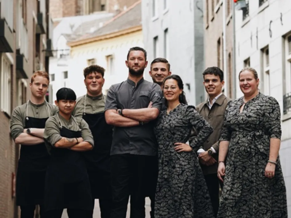 Das Team von Restaurant Rura posiert in einer Gasse in Roermond, mit Küchenchef Joey und Gastgeberin Naomi in der Mitte.