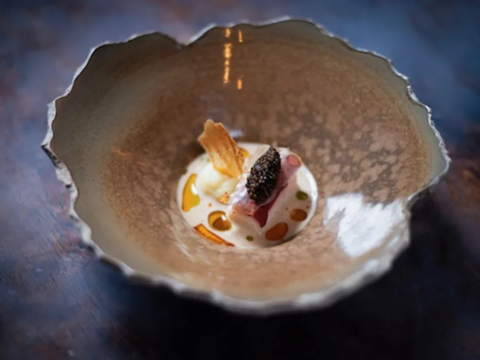 Refined starter in a handcrafted bowl, featuring fish, caviar, foam and colorful oils.