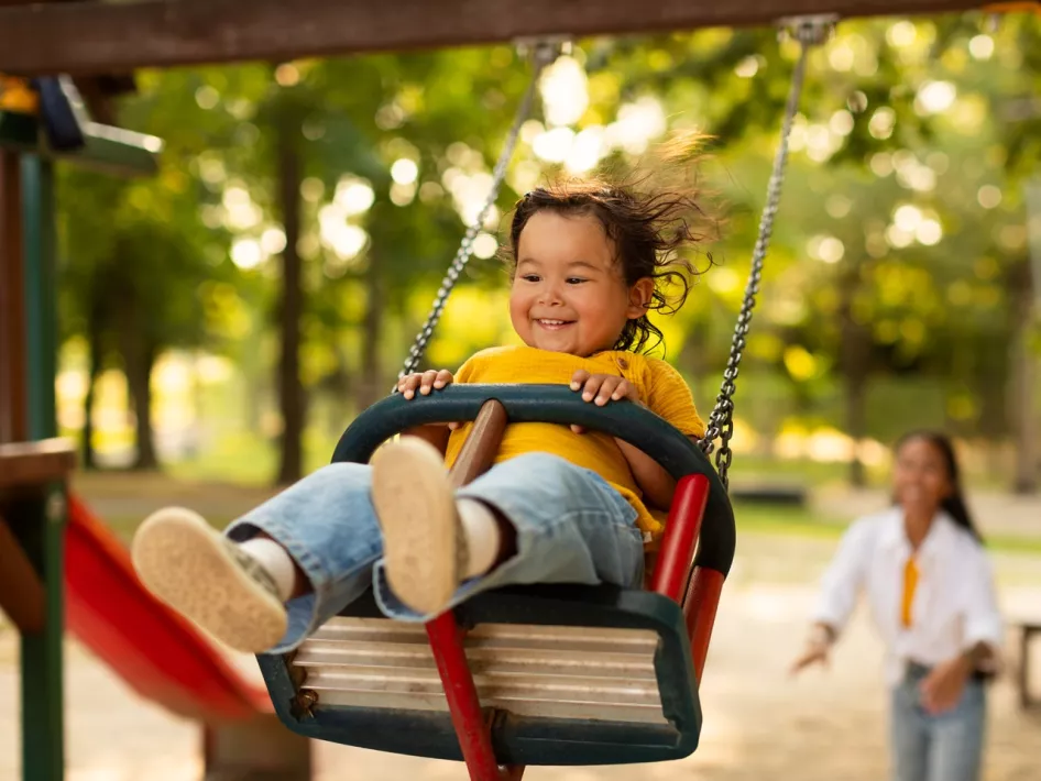 Meisje zit in de schommel en wordt geduwd door haar moeder in een van de speeltuinen die ligt aan de speeltuinroute Weert