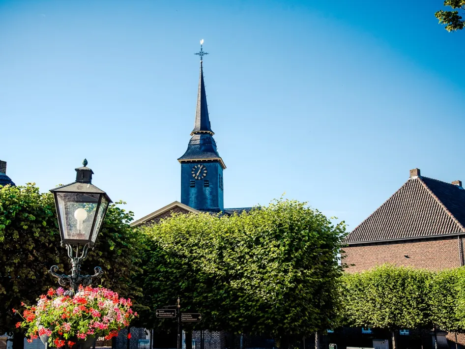 Kirche und Laterne zwischen grünen Bäumen im historischen Zentrum von Stevensweert