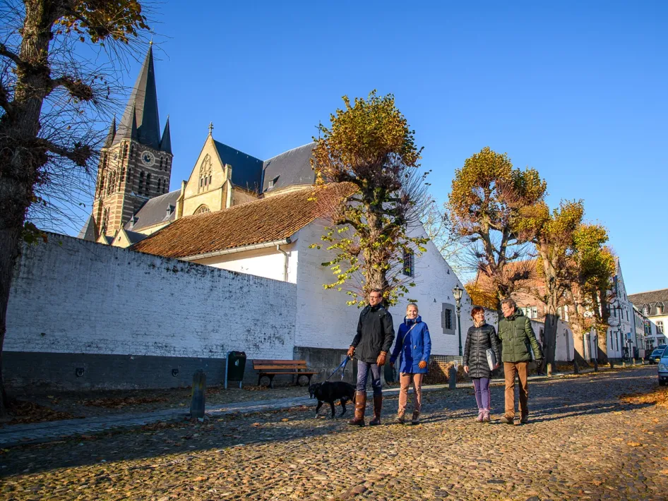 Spaziergänger in Herbstfarben schlendern durch die historischen Straßen von Thorn, die Abteikirche im Hintergrund.