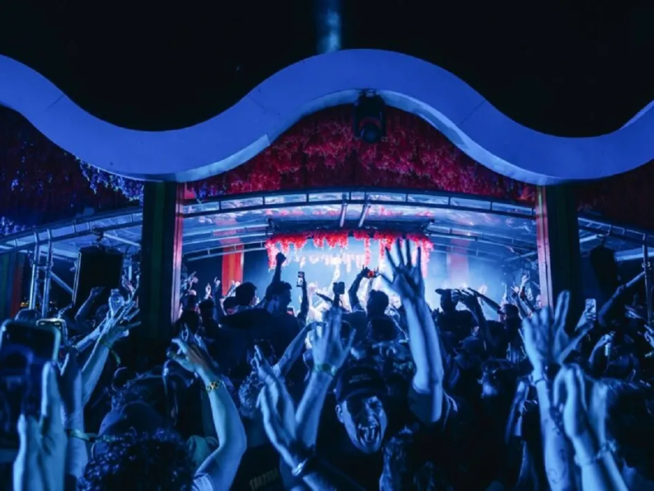 Dansende menigte met opgestoken handen in een sfeervol verlichte club tijdens STRAAL @ Weerstand in Roermond.