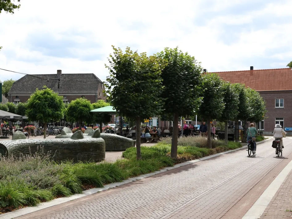 Straattheater Fietstocht in Beesel met fietsers op het Marktplein, waar terrassen, groen en het dorpsplein het decor vormen van het evenement.