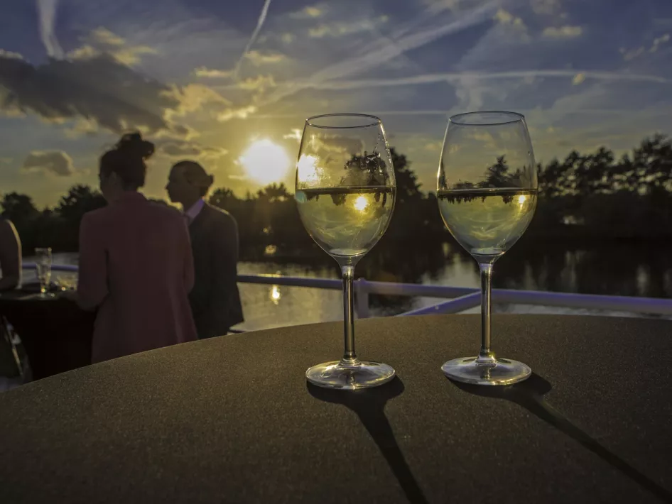 Glasses of white wine line the deck of the Sunset Cruise