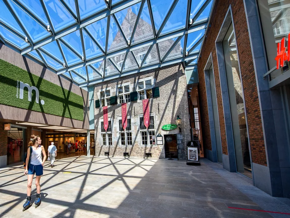 Woman on skates looks back at the historic building of Taverne de Oude Munt, located in the Muntpassage in Weert