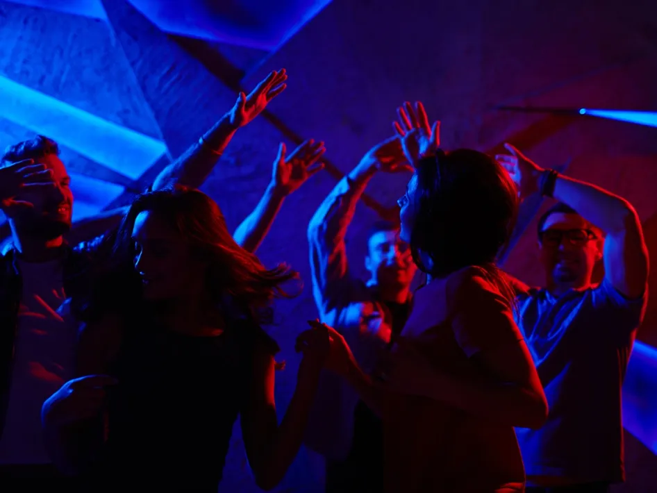 Mensen dansen op de dansvloer onder blauw en rood licht tijdens The Dancefloor Classics Beesel.