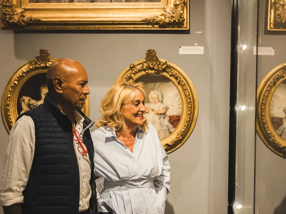Twee bezoekers bekijken portretten en andere historische objecten in de tentoonstelling Identiteit in beeld, van blazoen tot logo.
