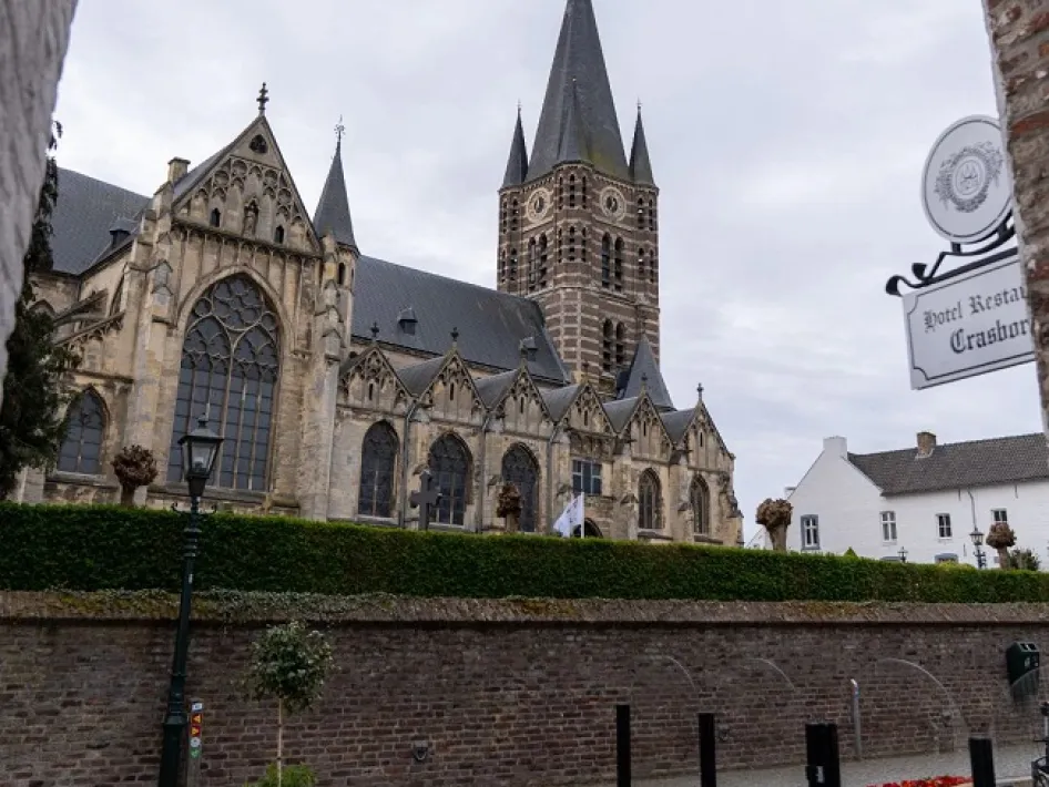 Zicht op de kerk van Thorn vanaf een straat met terras en uithangbord van Hotel-Restaurant Crasborn tijdens de Wandelarrangement Thorn