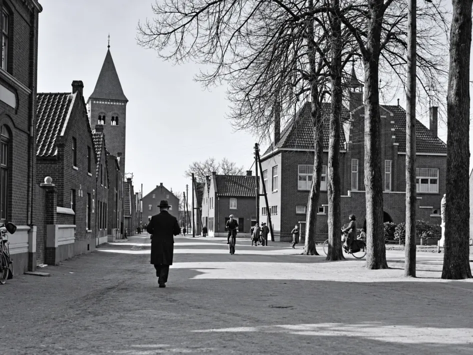 Historische dorpsstraat in Vlodrop met oude woningen, bomen en de kerktoren op de achtergrond, passend bij de VVV-wandeling Vlodrop.