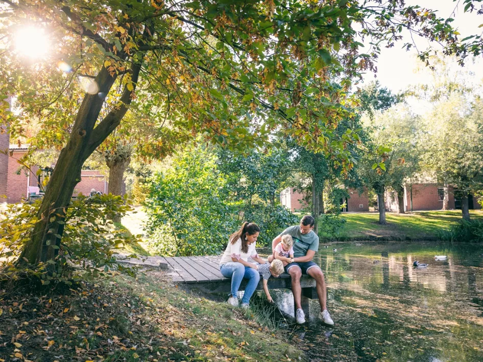 Gezin zit op de steiger aan het water van Vakantiepark Weerterbergen