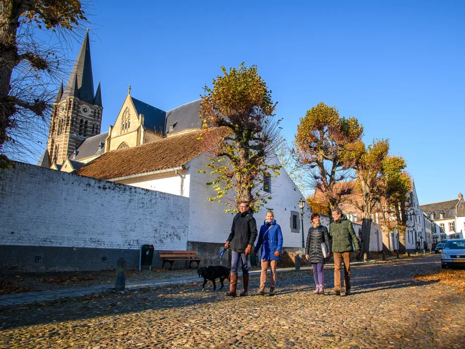 Bezoekers wandelen door het historische centrum van Thorn tijdens de VVV Vakantiewandeling, met de Abdijkerk en witte huizen op de achtergrond.