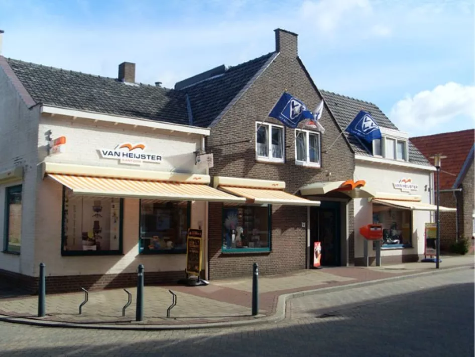 Vooraanzicht van Van Heijster Kantoor/Boekado in Swalmen met VVV Servicepunt, voorzien van oranje markiezen en VVV-vlaggen.