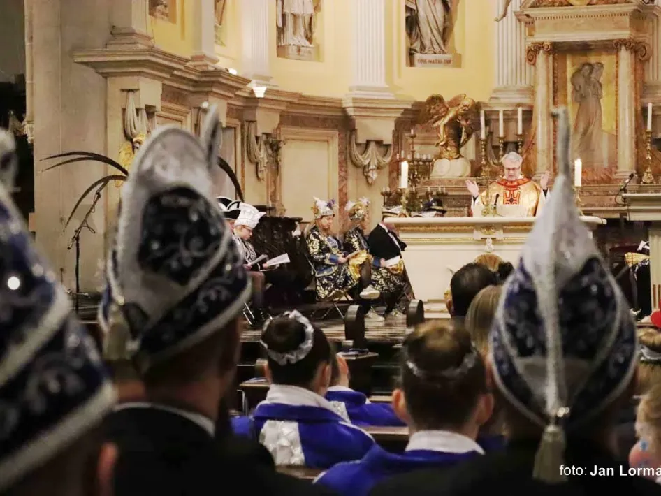 Vastelaovendjmés in de St. Martinuskêrk in Weert, met Rogstaekers in traditionele steek en muzikanten bij het altaar.