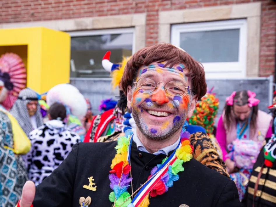 Feestelijke sfeer bij Vastelaoves Villaasj – Een vrolijke carnavalsvierder met kleurrijke schmink en een feestelijke outfit geniet van de gezelligheid op Vastelaoves Villaasj.