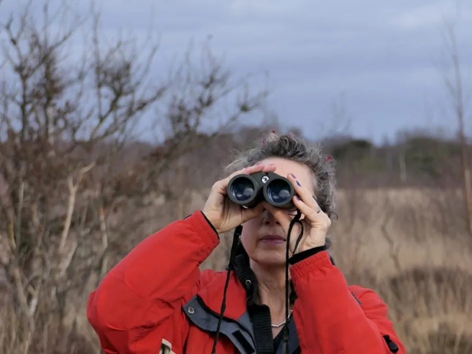 Vrouw kijkt door verrekijker tijdens de vogelexcursie in de Deurnese Peel