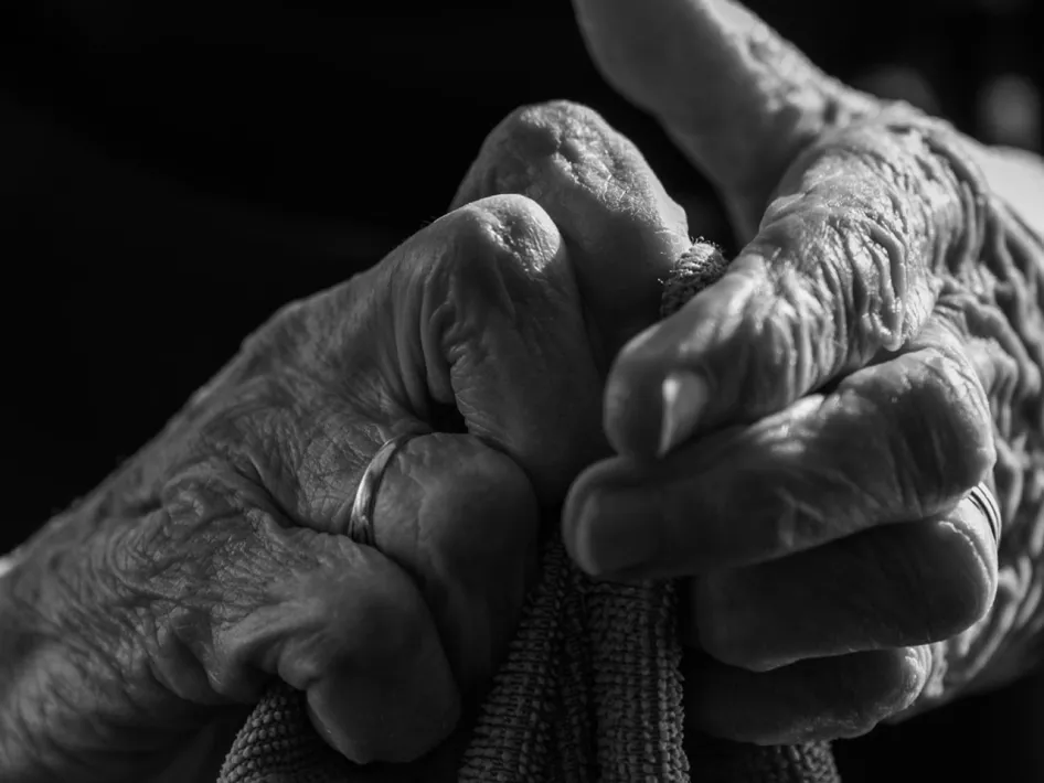 Zwart-witfoto van twee oudere vrouwenhanden die een doek vasthouden, met zichtbaar kraakbeen, rimpels en ringen aan de vingers. Onderdeel van de expositie Vrouwenhanden in het Museum van de Vrouw.