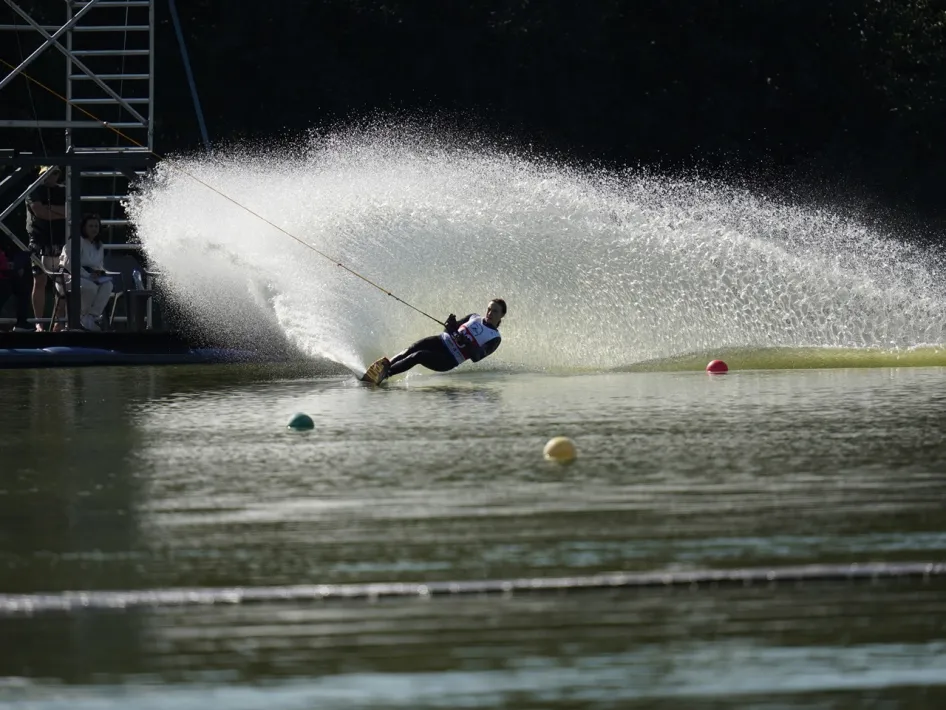 Waterskiër maakt een scherpe bocht op het water met een hoge boog van opspattend water.