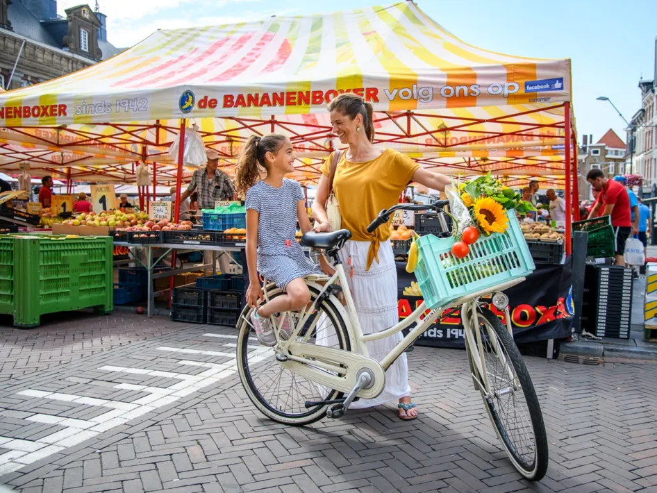 Mother and daughter with a bicycle in front of a market stall at the weekly market Roermond.