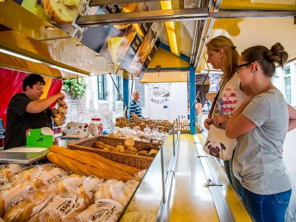 Mensen bij de bakkerskraam op de weekmarkt Weert