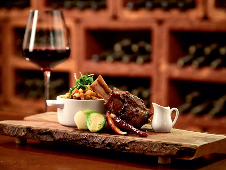 Wildgerecht met rode wijn tijdens het Wild en Wijn Festijn bij Parkhotel Horst, geserveerd op een robuuste houten plank met herfstige presentatie.