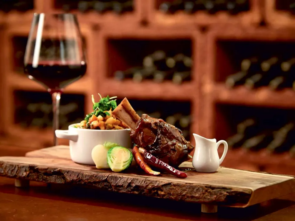 Sfeervol opgediend wildgerecht met glas rode wijn tijdens de Wild & Wijn avond in het kasteel in Hart van Limburg