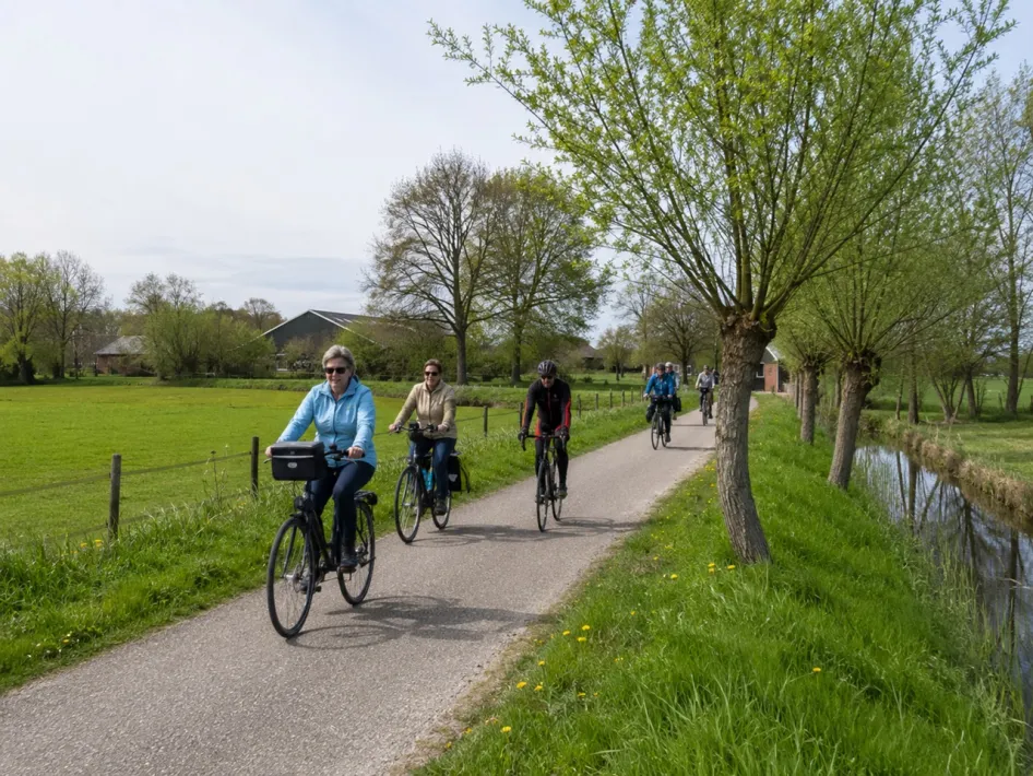 Een kleine groep fietsers rijdt tijdens de Zeevershofronde over een rustig fietspad door het groene boerenlandschap rond Hunsel.